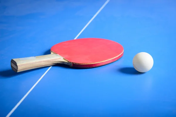 Pin Pong Ball mit rotem Paddel auf blauem Brett — Stockfoto