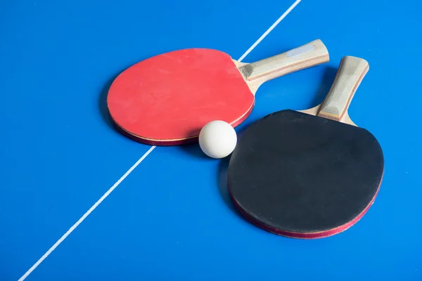 Pin pong bola con paleta roja en el tablero azul — Foto de Stock