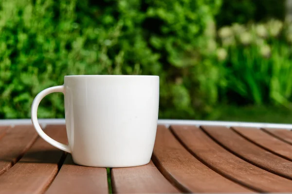 Kaffekopp i grönskande trädgård på bord — Stockfoto