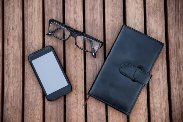 Mobile phone, glasses, calculator, notepad on wooden table. Business accessories concept. — Stock Photo, Image