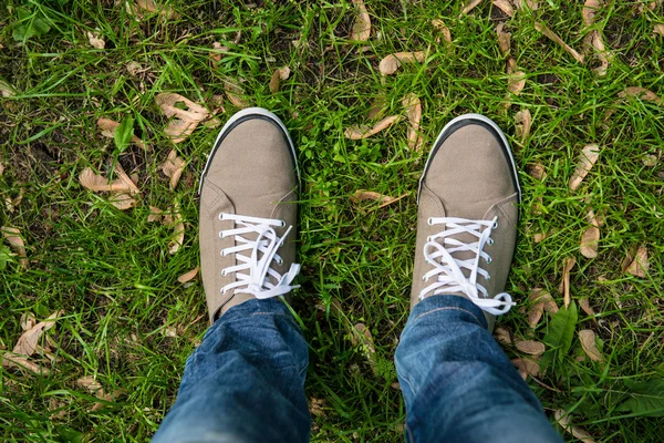 Человек в ботинках жвачки стоит на зеленой траве — стоковое фото