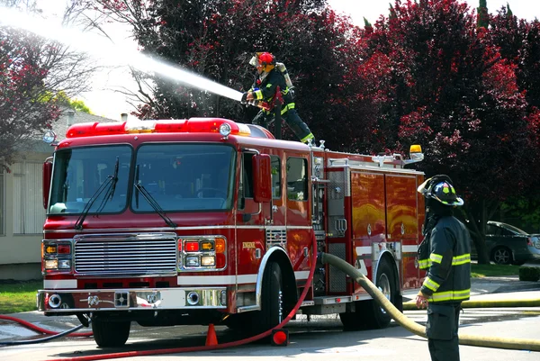 Brandweerlieden en brand vrachtwagen op een appartement brand Rechtenvrije Stockfoto's