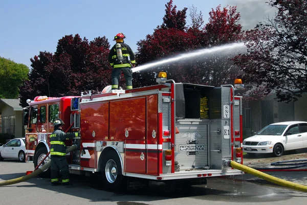 Bomberos y camión de bomberos en un incendio apartamento —  Fotos de Stock