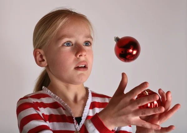 Girl juggling with red Cristmas toy — Stock Photo, Image