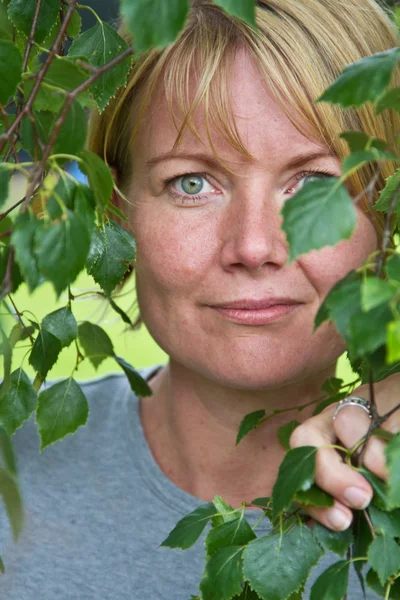 Mature woman in green leaves — Stock Photo, Image