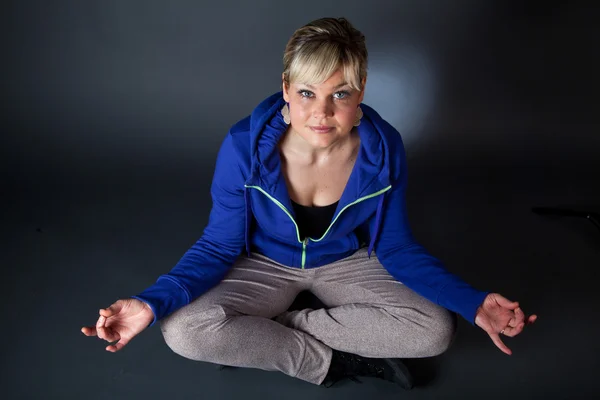 Stúdió portré egy aranyos szőke lány, egy meditációs pozícióban — Stock Fotó