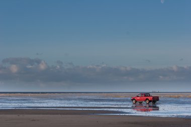 Red car on the beach Island of Fanoe in Denmark clipart
