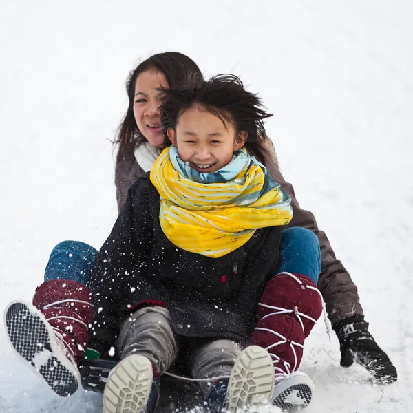 Two sisters sledging holding each other — Stock Photo, Image