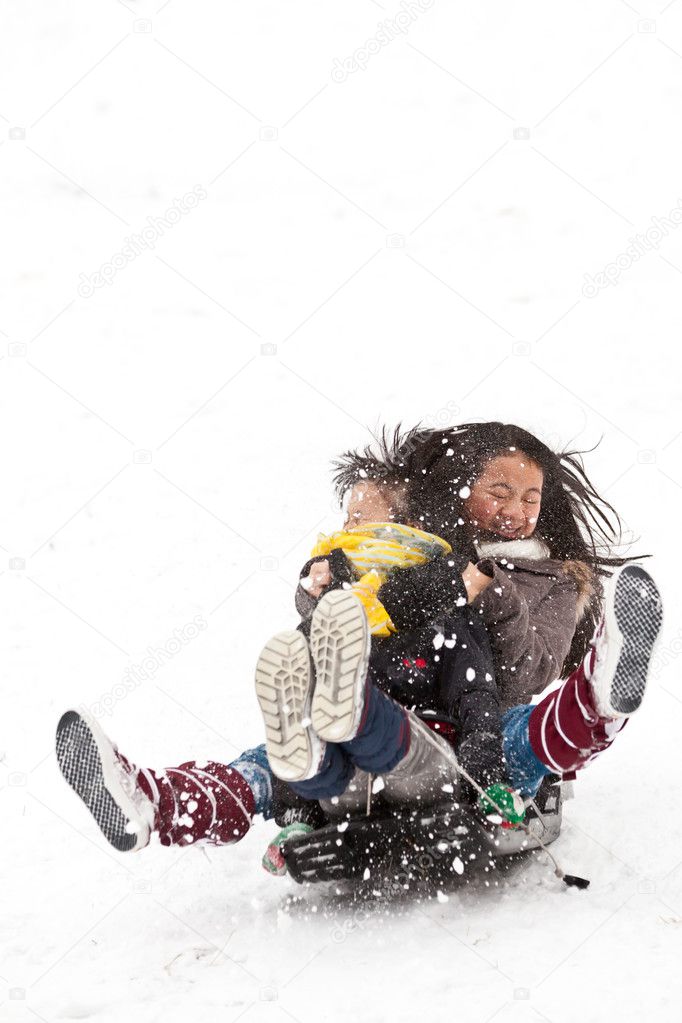 Two sisters sledging holding each other