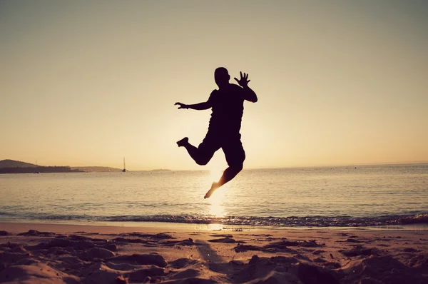 Muž skok v západu slunce na pláži — Stock fotografie