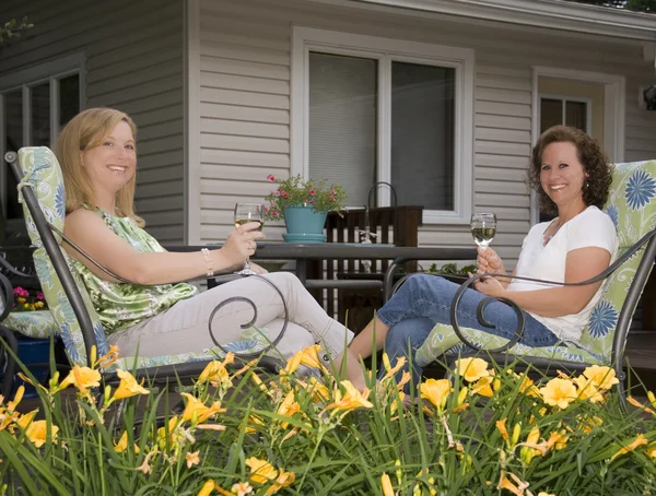 Femmes sur le patio encadré par des fleurs Image En Vente