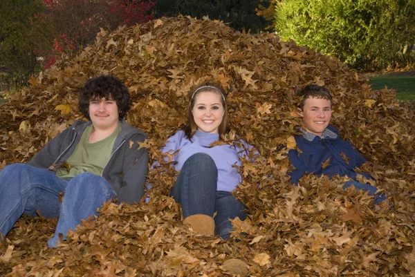 Raking Leaves Three Teens Sitting in Leaf Pile — Stock Photo, Image