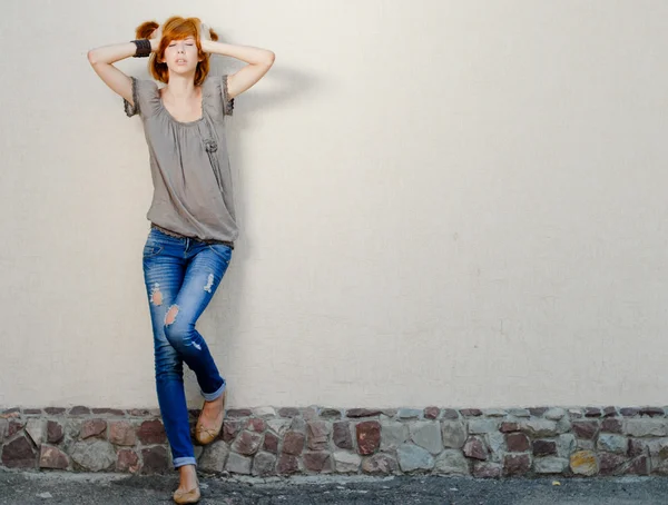 Young beautiful slim woman standing near wall negative space — Stock Photo, Image