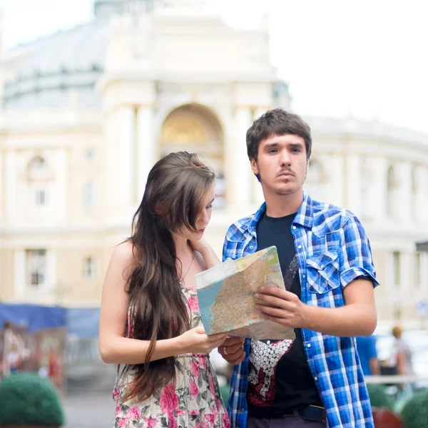 Casal jovem olhando no mapa no centro da cidade e mostrando a direção — Fotografia de Stock