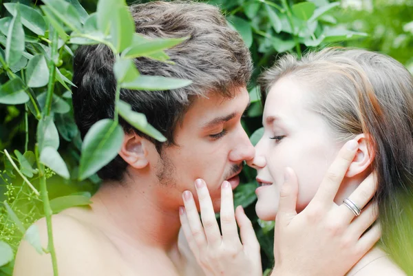 Yeşil yaprakları arasında şefkatle kucaklayan genç mutlu çift — Stok fotoğraf