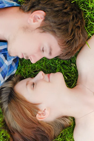 Jovem casal feliz homem e mulher deitado no gramado verde — Fotografia de Stock