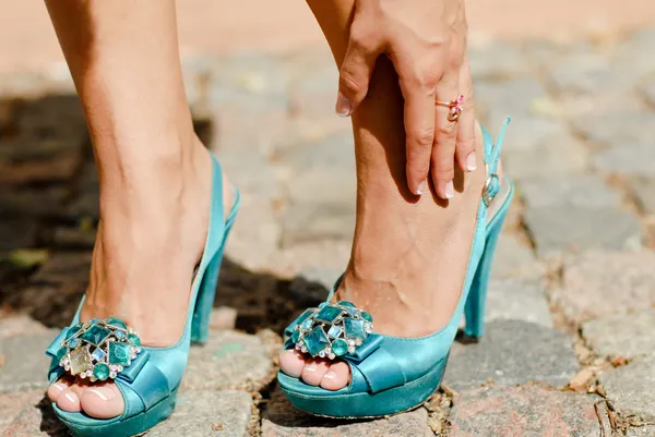 Beautiful woman legs in blue high heel shoes touching ankle in p — Stock Photo, Image