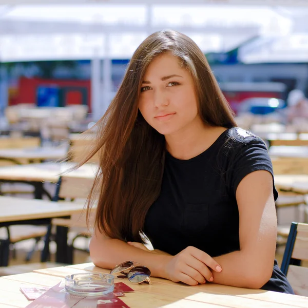 Young beautiful woman sitting at cafe table on open terrace — Stock Photo, Image