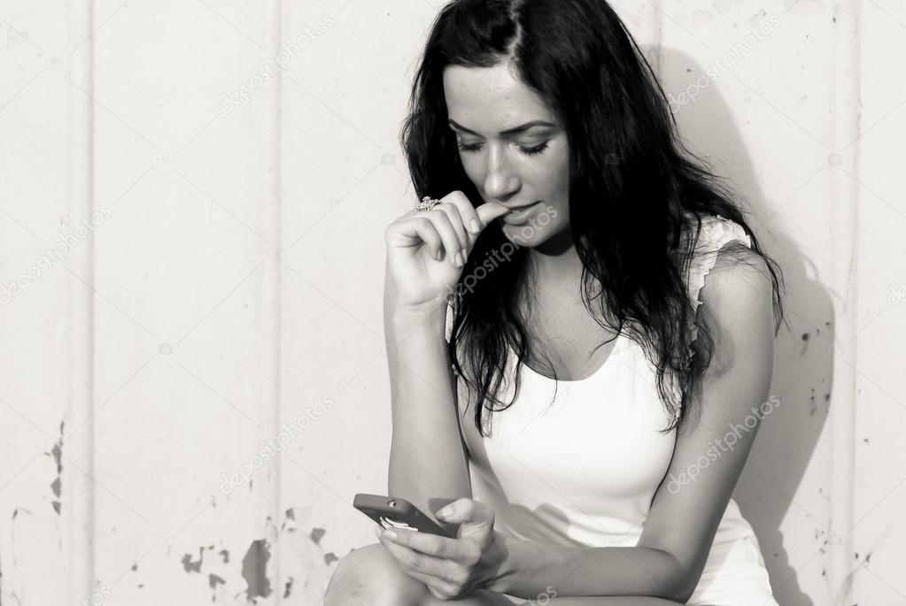 Young beautiful woman reading message on mobile touch phone