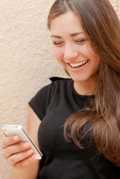 Молодая счастливая женщина читает сообщения по мобильному телефону и смеется — стоковое фото