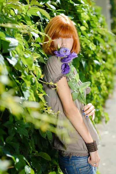 Menina adolescente ruiva bonita com roxo rosa por folhas verdes bac — Fotografia de Stock