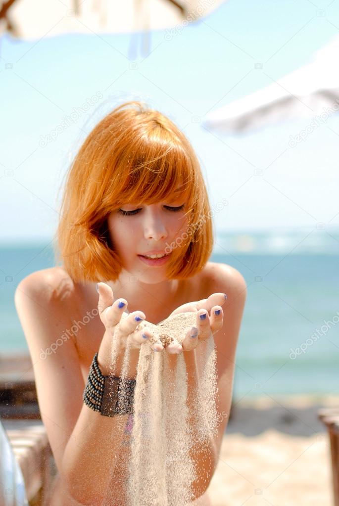 Young beautiful redhead woman in bikini on sea coast