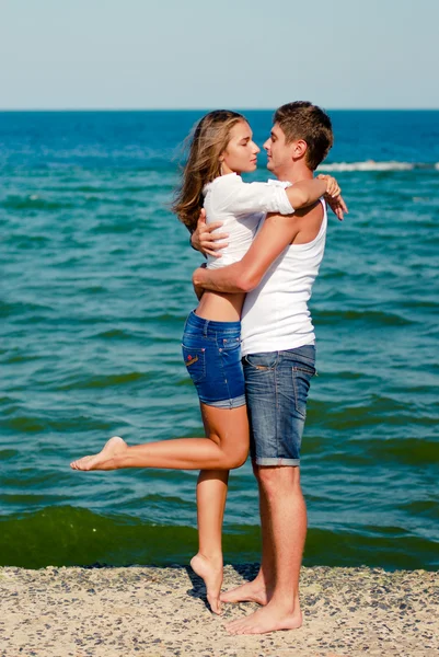 Young happy couple embracing on sea coast — Stock Photo, Image