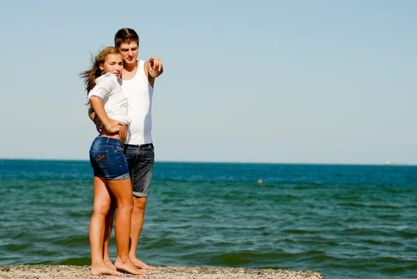 Joven feliz pareja abrazando en la costa del mar — Foto de Stock