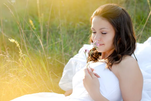 Jeune belle mariée sentant la fleur couchée dans l'herbe verte — Photo