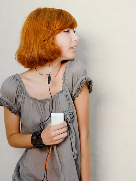 Young beautiful redhead girl listening to player — Stock Photo, Image