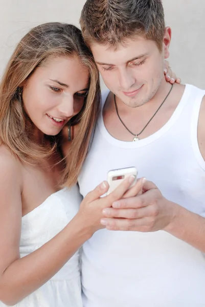 Joven pareja feliz mirando en el teléfono móvil con interés —  Fotos de Stock