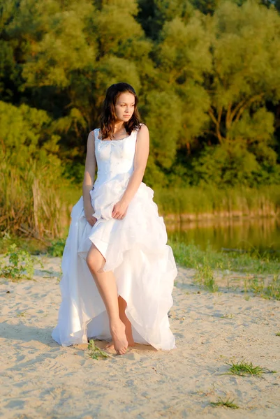 Giovane bella sposa in piedi vicino al fiume premuroso — Foto Stock