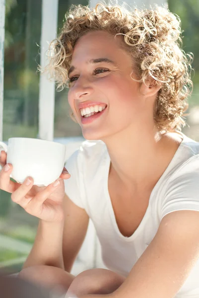 Молодая счастливая женщина пьет утреннюю чашку кофе — стоковое фото