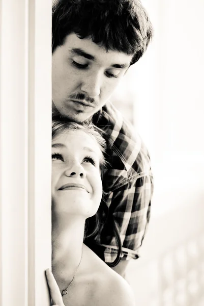 Young happy couple looking round the corner at each other — Stock Photo, Image