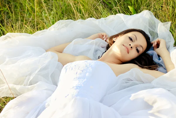 Jovem noiva bonita deitada na grama verde — Fotografia de Stock