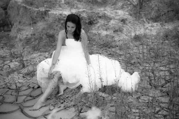 Young beautiful bride sitting in desert — Stock Photo, Image