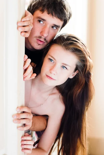 Young happy couple looking round the corner interested — Stock Photo, Image