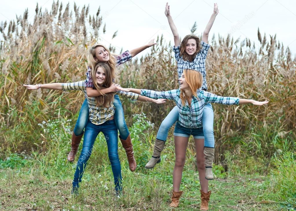 Four happy teen girls friends having fun outdoors