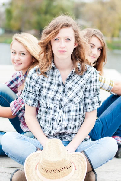 Drei glückliche Mädchen, die zusammen draußen sitzen — Stockfoto