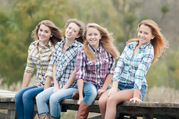 Four girls sitting on river bridge — Stock Photo, Image