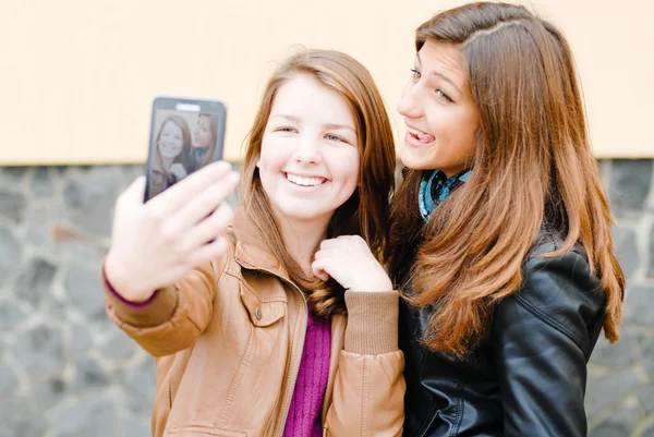 Duas meninas adolescentes tirando fotos de si mesmas usando tablet pc — Fotografia de Stock