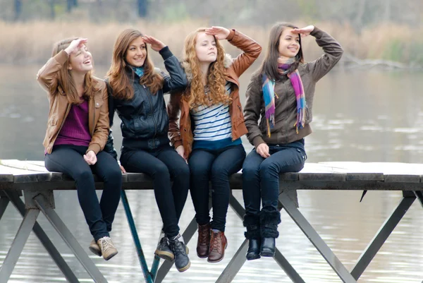 Four school girls sitting on river bridge — Stock Photo, Image