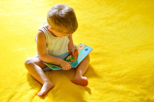 Piccolo divertente ragazzo lettura libro a casa — Foto Stock