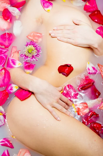 Сексуальна молода жінка в ванні з пелюсткою квітів . — стокове фото
