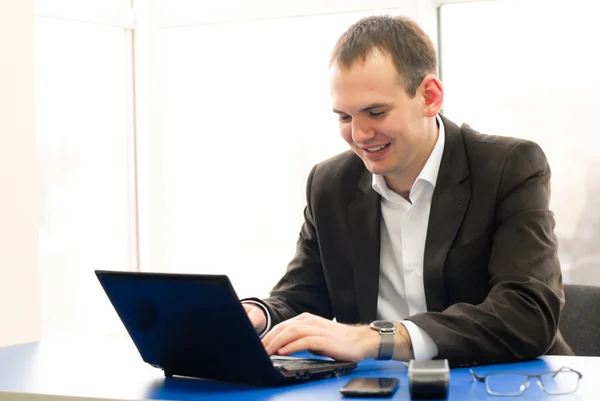 Happy businessman using laptop in building, smiling. — Stock Photo, Image