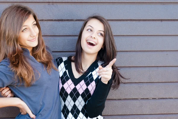 Dos amigas adolescentes muy felices riéndose y apuntando al espacio de copia —  Fotos de Stock