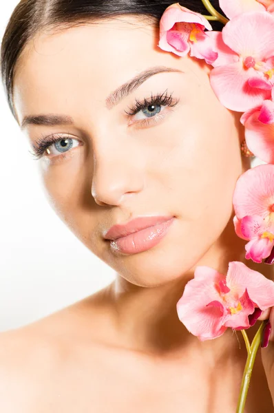 Hermosa cara de niña y flores de color rosa, piel perfecta y labios . —  Fotos de Stock