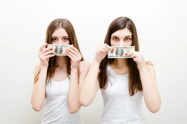 Silenciados por el dinero. Retrato de dos hermosas mujeres jóvenes mostrando dinero. Estudio sobre fondo blanco — Foto de Stock