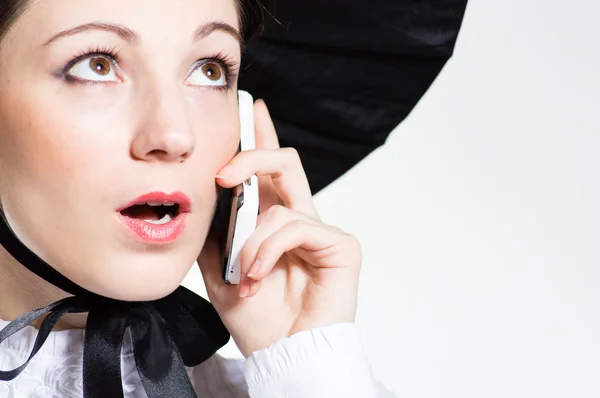 Mujer joven sorprendida con teléfono móvil mirando en copyspace sobre fondo blanco — Foto de Stock