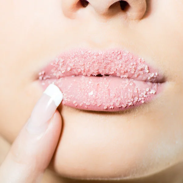 Primer plano en los labios dulces azucarados femeninos con el dedo bien cuidado — Foto de Stock